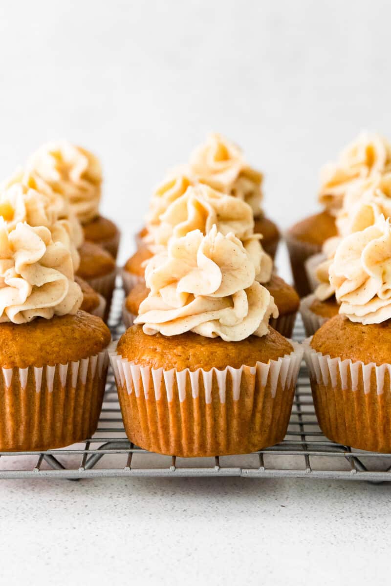 9 gingerbread cupcakes topped with spiced white chocolate buttercream on a cooling rack