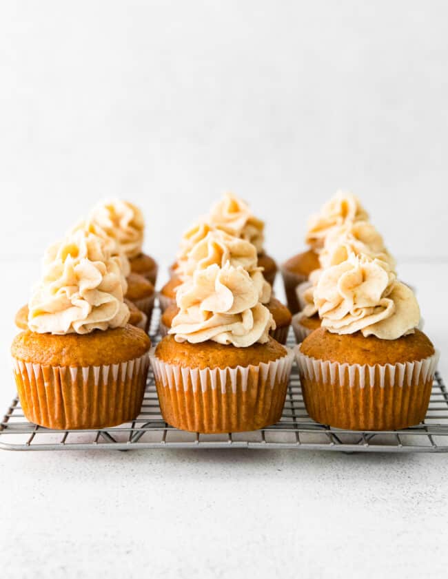 9 gingerbread cupcakes topped with spiced white chocolate buttercream on a cooling rack