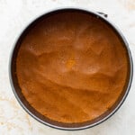 a brown cake in a pan on a white surface.