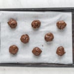 8 chocolate cake mix cookies with chocolate chips on a parchment lined baking sheet before baking
