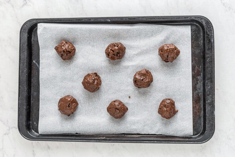 8 chocolate cake mix cookies with chocolate chips on a parchment lined baking sheet before baking