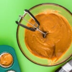 pumpkin cupcake batter in a glass bowl with a cookie scoop