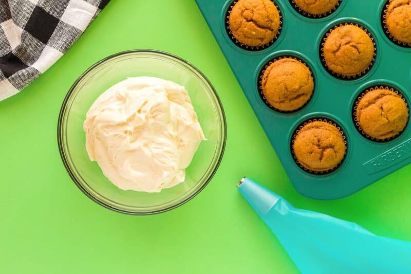 cream cheese frosting in a clear bowl with a piping bag