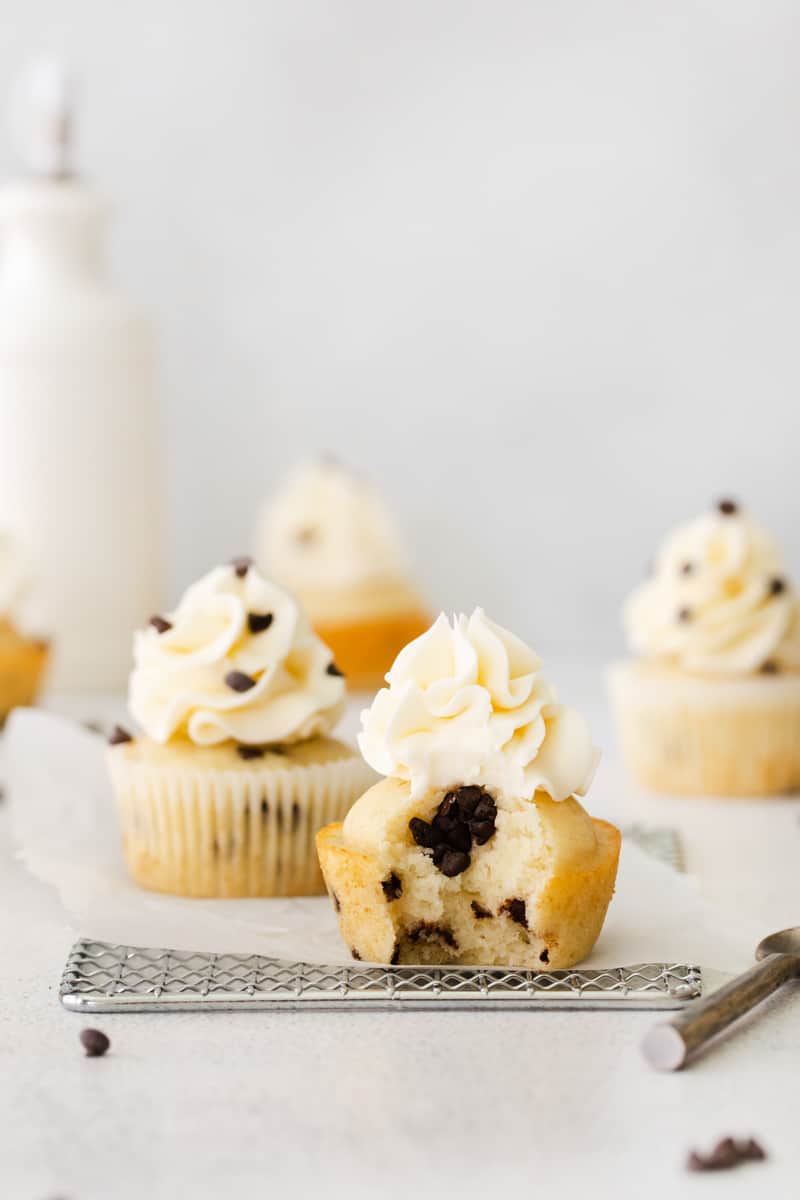 chocolate chip cupcakes topped with frosting and chocolate chips with a bite taken from one