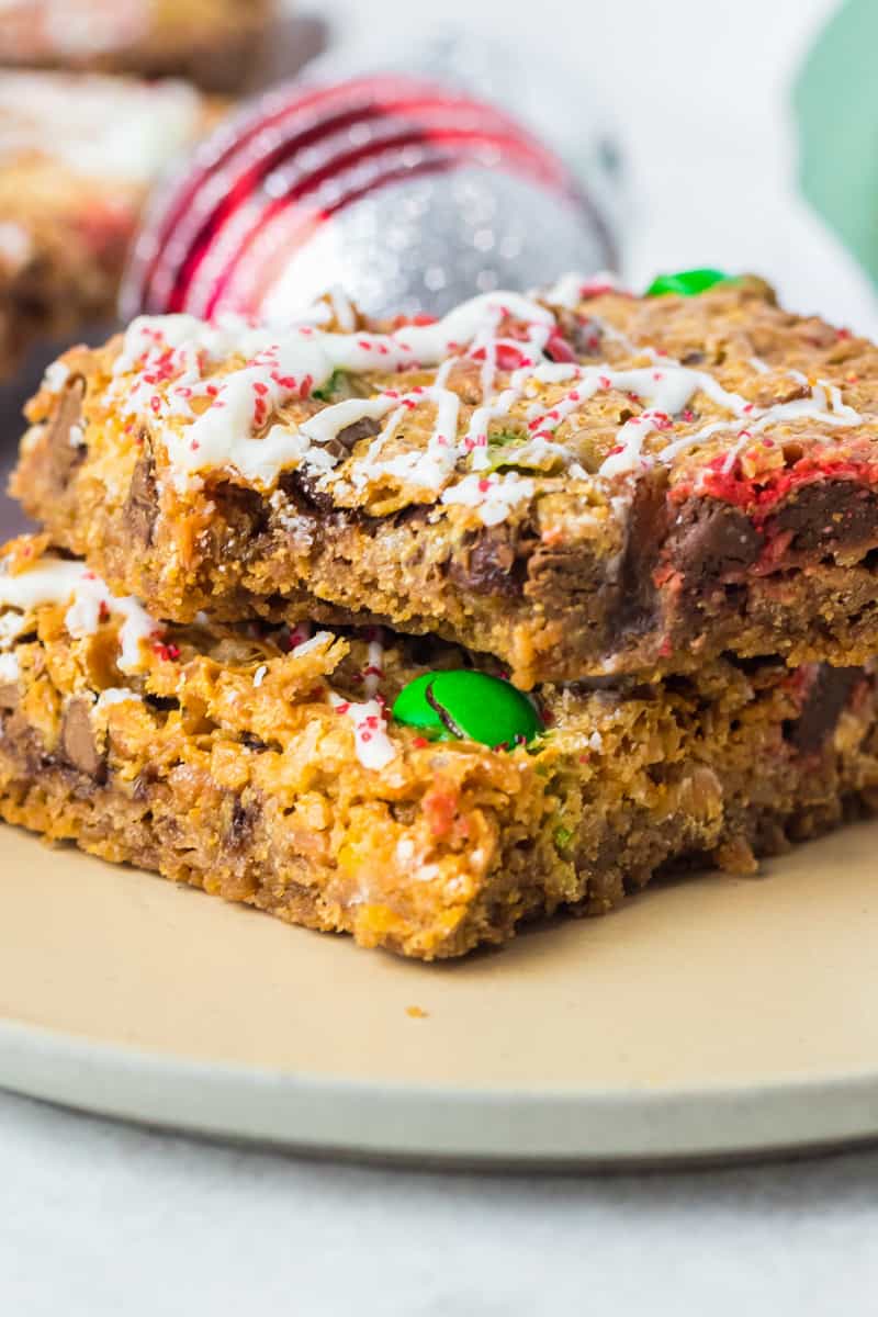 2 christmas 7 layer magic cookie bars on a white plate with a bite taken from one