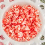 overhead view of red and white christmas cream cheese mints in a milk glass bowl.