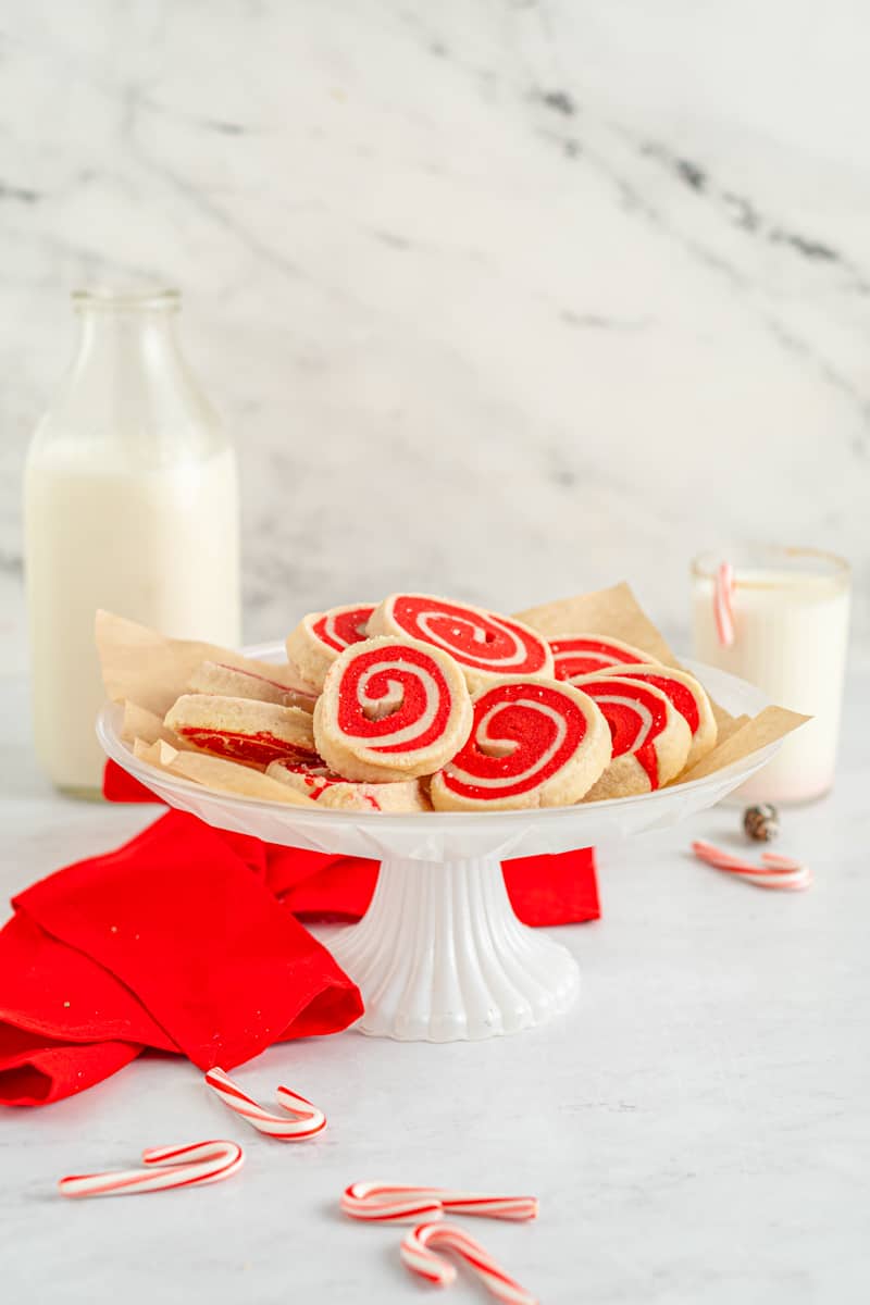 white and red pinwheel cookies on a white cake stand