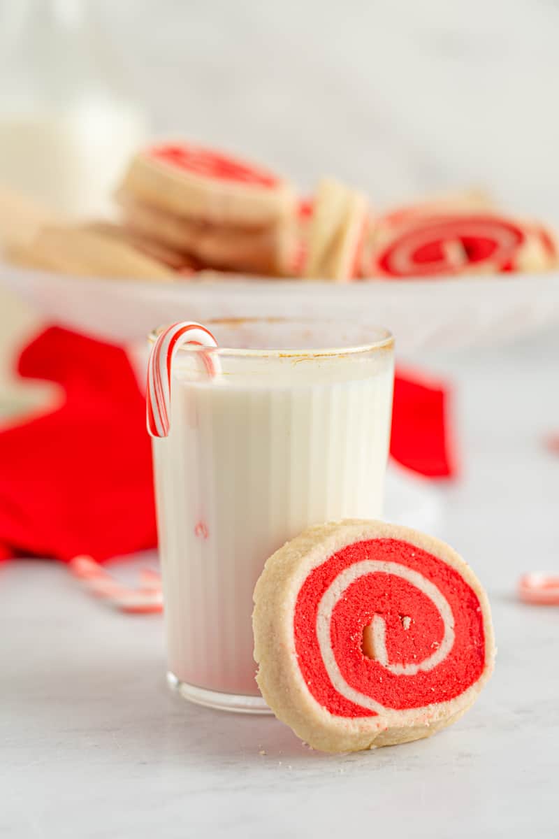 glass of milk with a red and white pinwheel cookie leaned against it