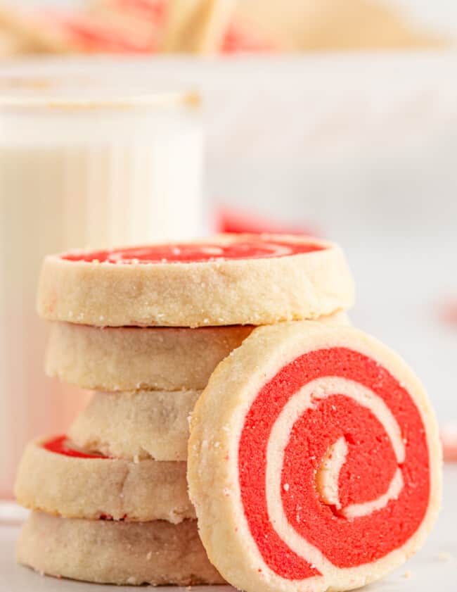stack of white and red pinwheel cookies with one leaned up showing the swirl