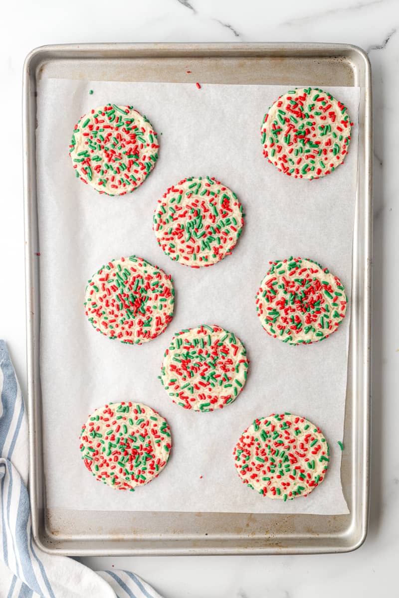 sugar cookies with red and green sprinkles on a baking sheet after baking
