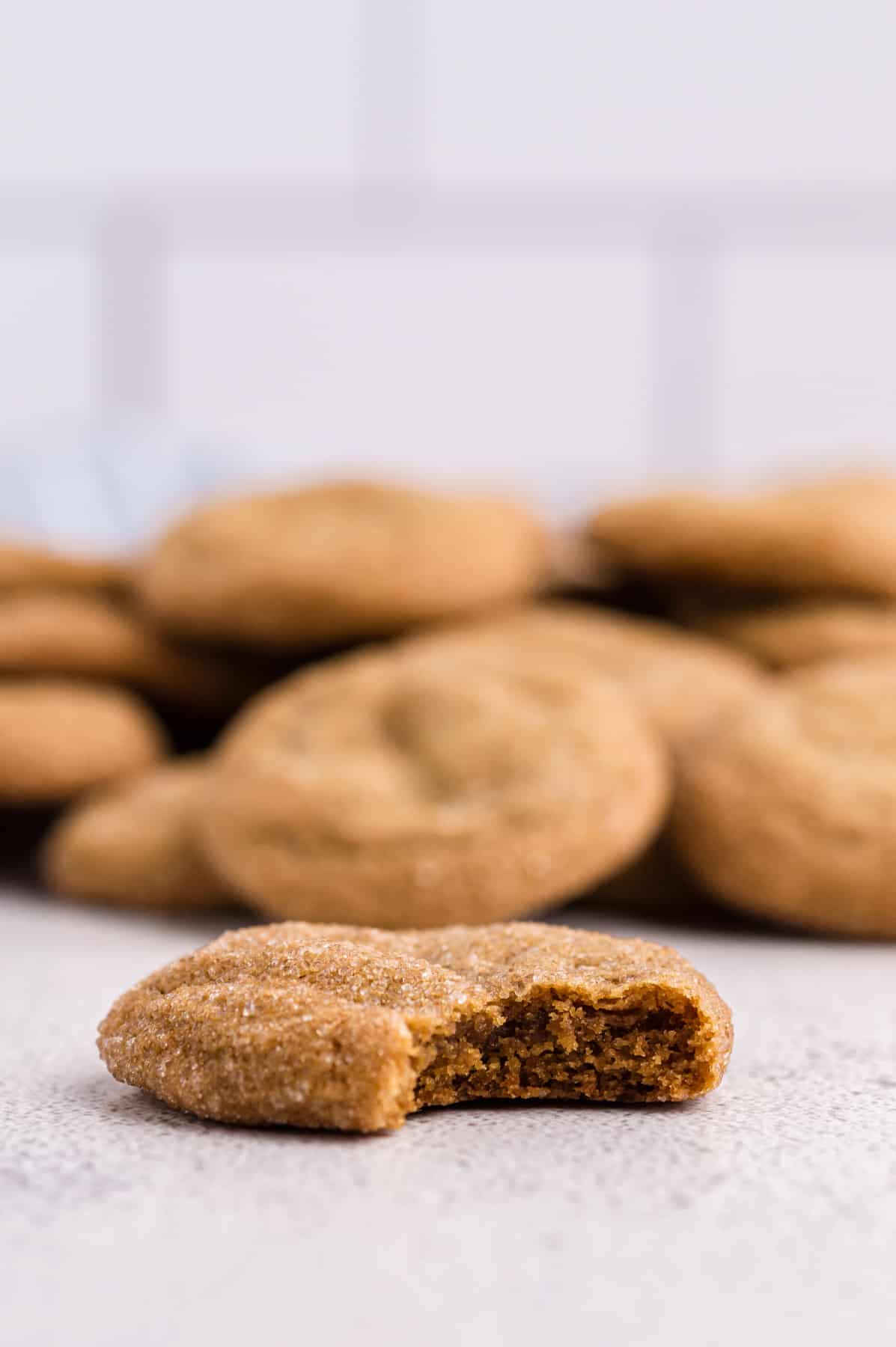 a bitten ginger molasses cookie in front of a pile of more cookies.