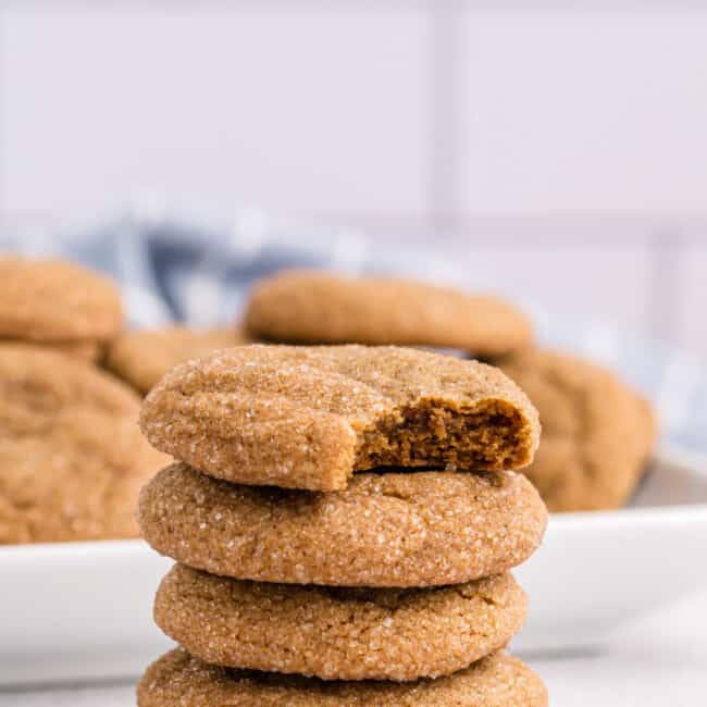 a bitten ginger molasses cookie on top of a stack of 4 ginger molasses cookies.