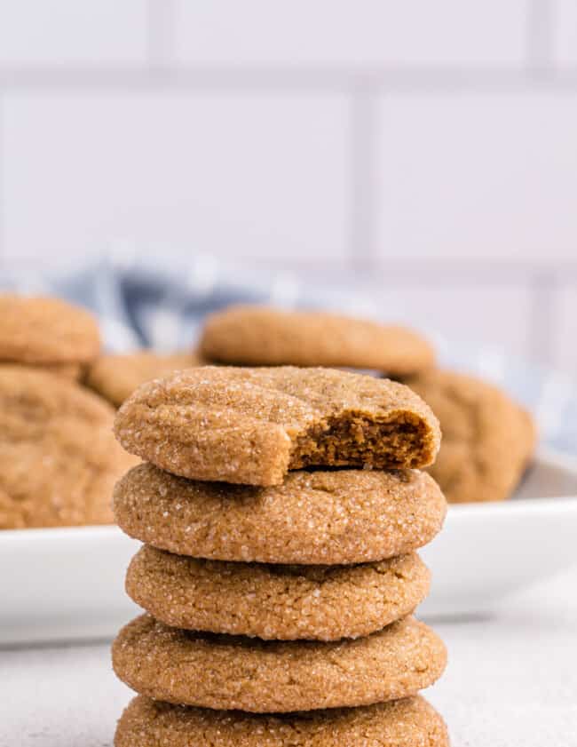 a bitten ginger molasses cookie on top of a stack of 4 ginger molasses cookies.