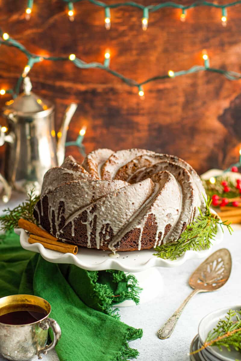 gingerbread bundt cake on a white cake stand with cake server.