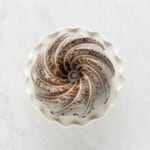 overhead view of glazed gingerbread bundt cake on a white cake stand.