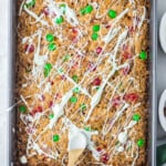 drizzling white chocolate onto magic cookie bars in a baking pan