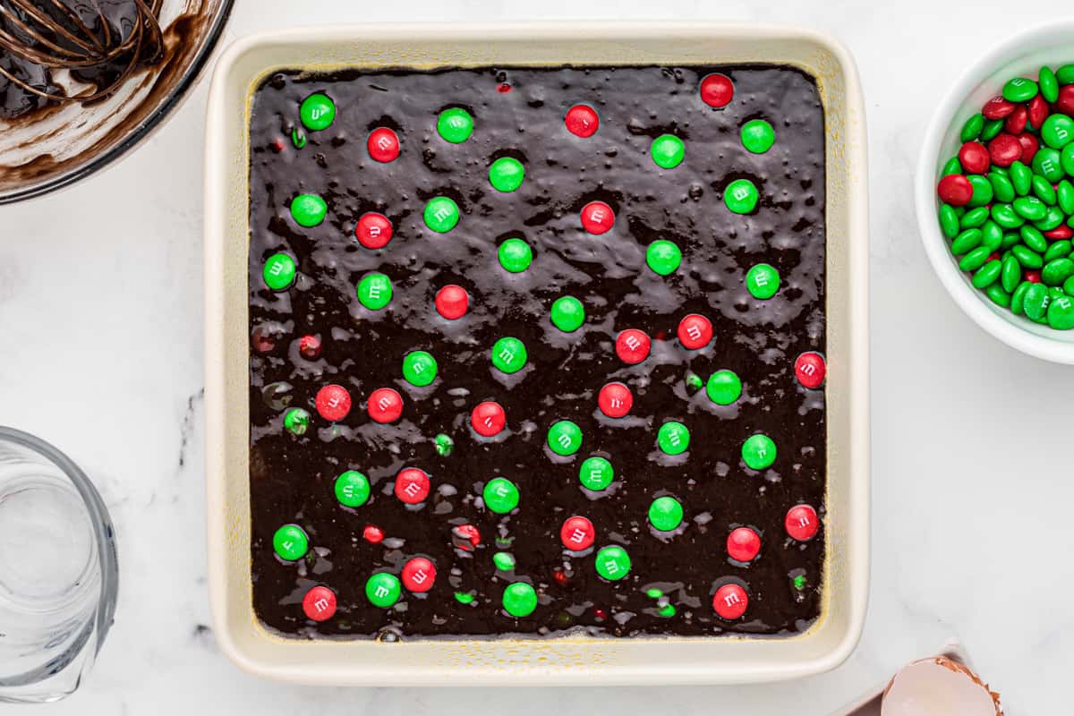 brownies with christmas M&Ms in a white baking dish before baking