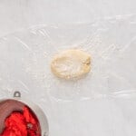 white cookie dough on plastic wrap before rolling out