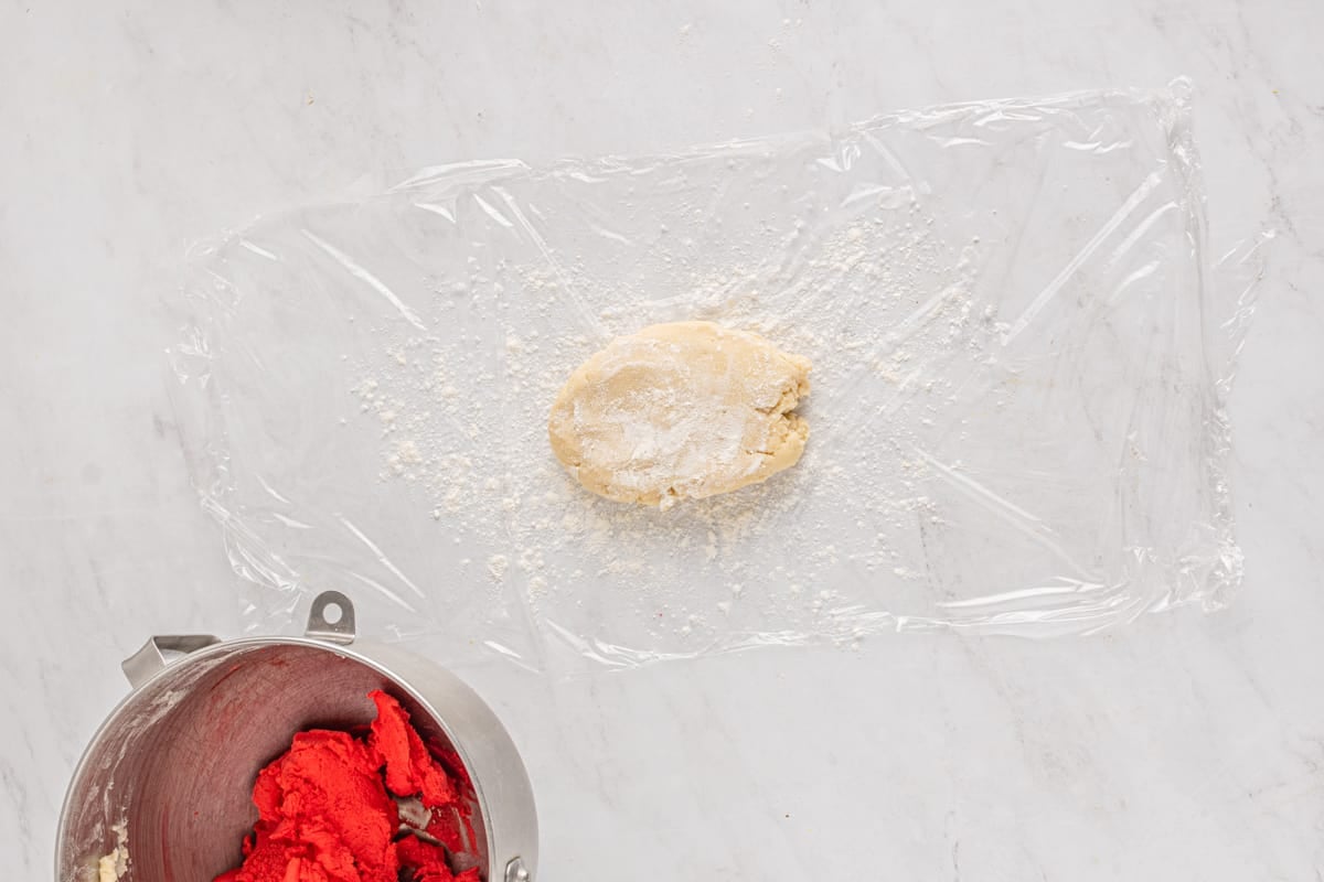 white cookie dough on plastic wrap before rolling out