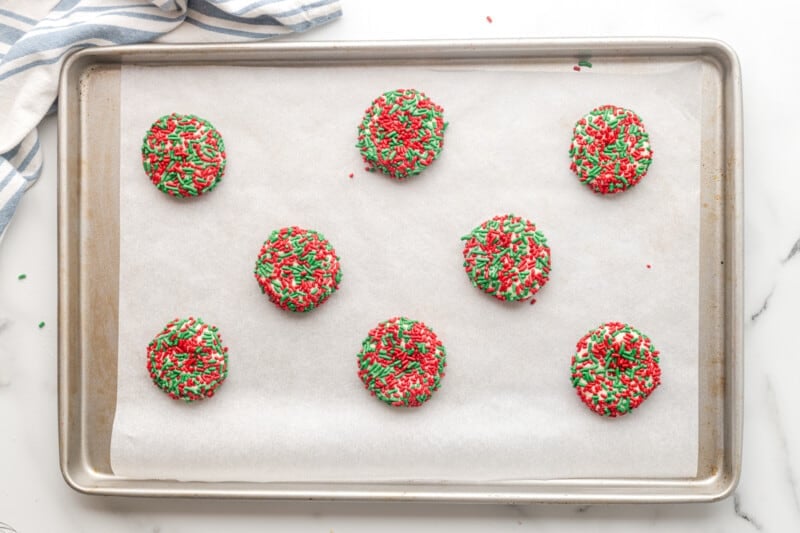 sugar cookies with red and green sprinkles on a baking sheet before baking