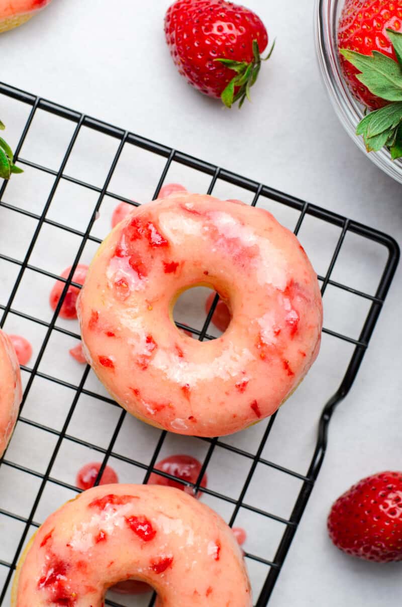 overhead image of baked strawberry donut with strawberry glaze on a cooling rack