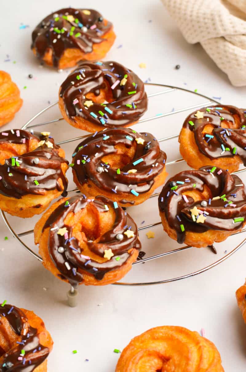 chocolate glazed crullers on a cooling rack
