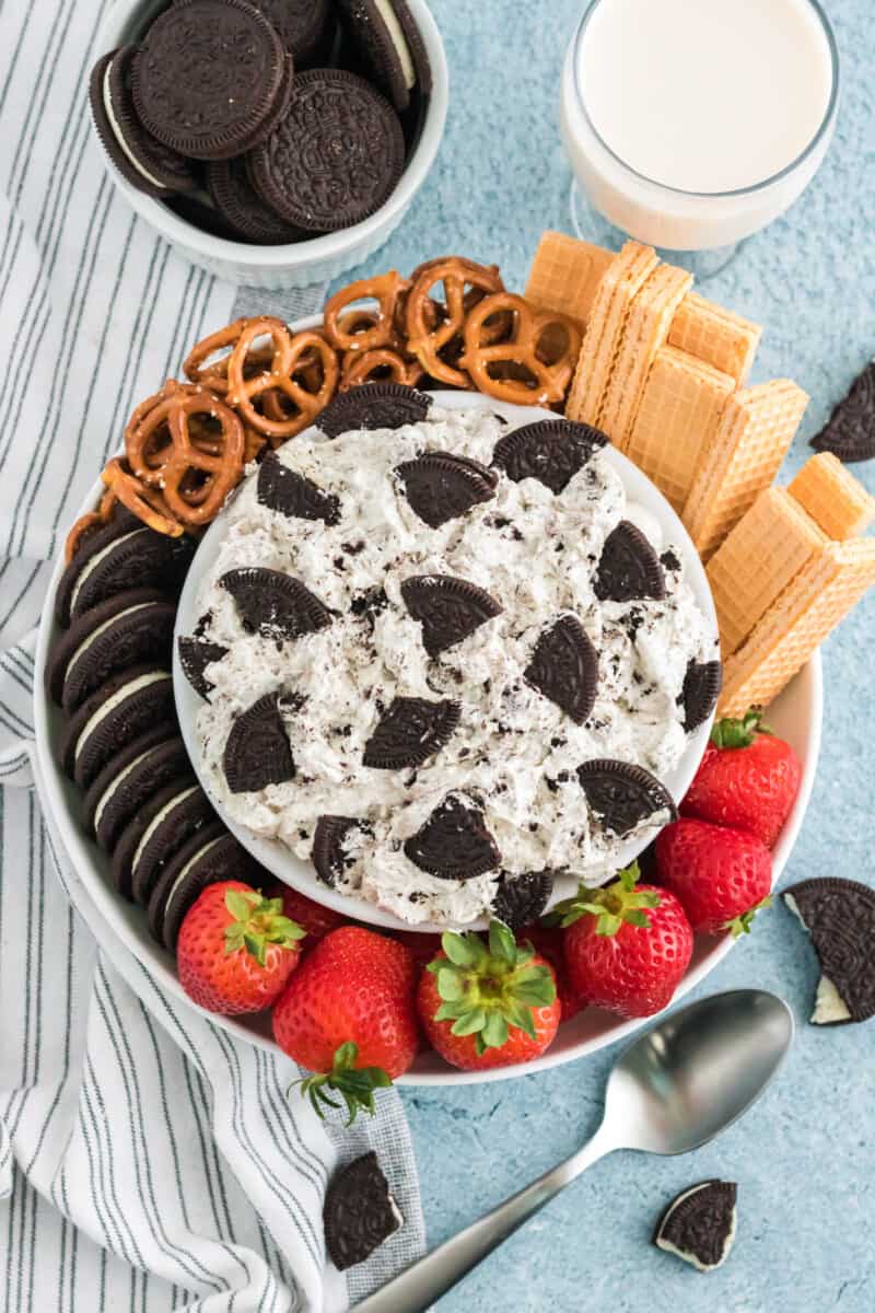 cookies and cream dip in a white bowl on a platter with Oreo cookies, pretzels, vanilla wafer cookies, and strawberries