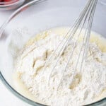 wet and dry ingredients in a glass bowl with a whisk