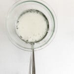 whisked egg whites and granulated sugar mixture in a glass bowl over a saucepan