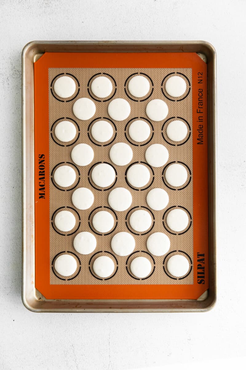macaron shells on a silpat mat lined baking sheet after baking
