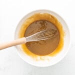 melted butter, brown sugar, egg, and vanilla in a white bowl with a whisk