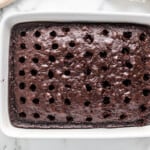 baked chocolate cake in a white baking dish with holes poked in it
