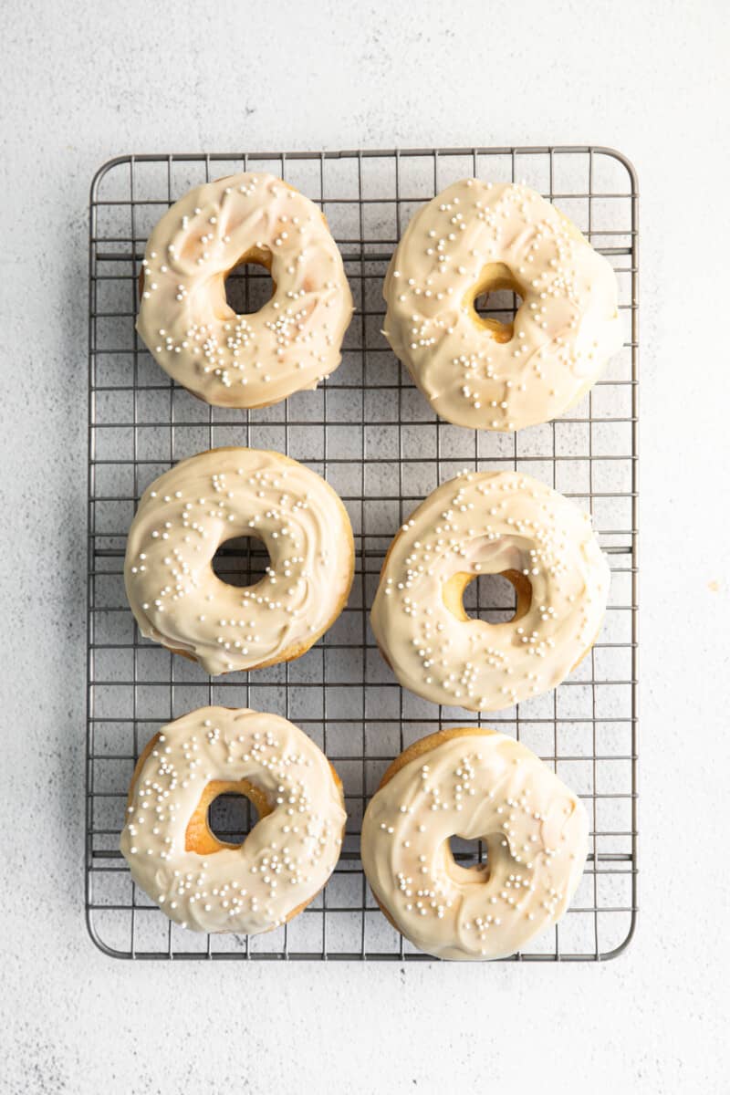overhead image of 6 coffee donuts with coffee icing and sprinkles on a cooling rack