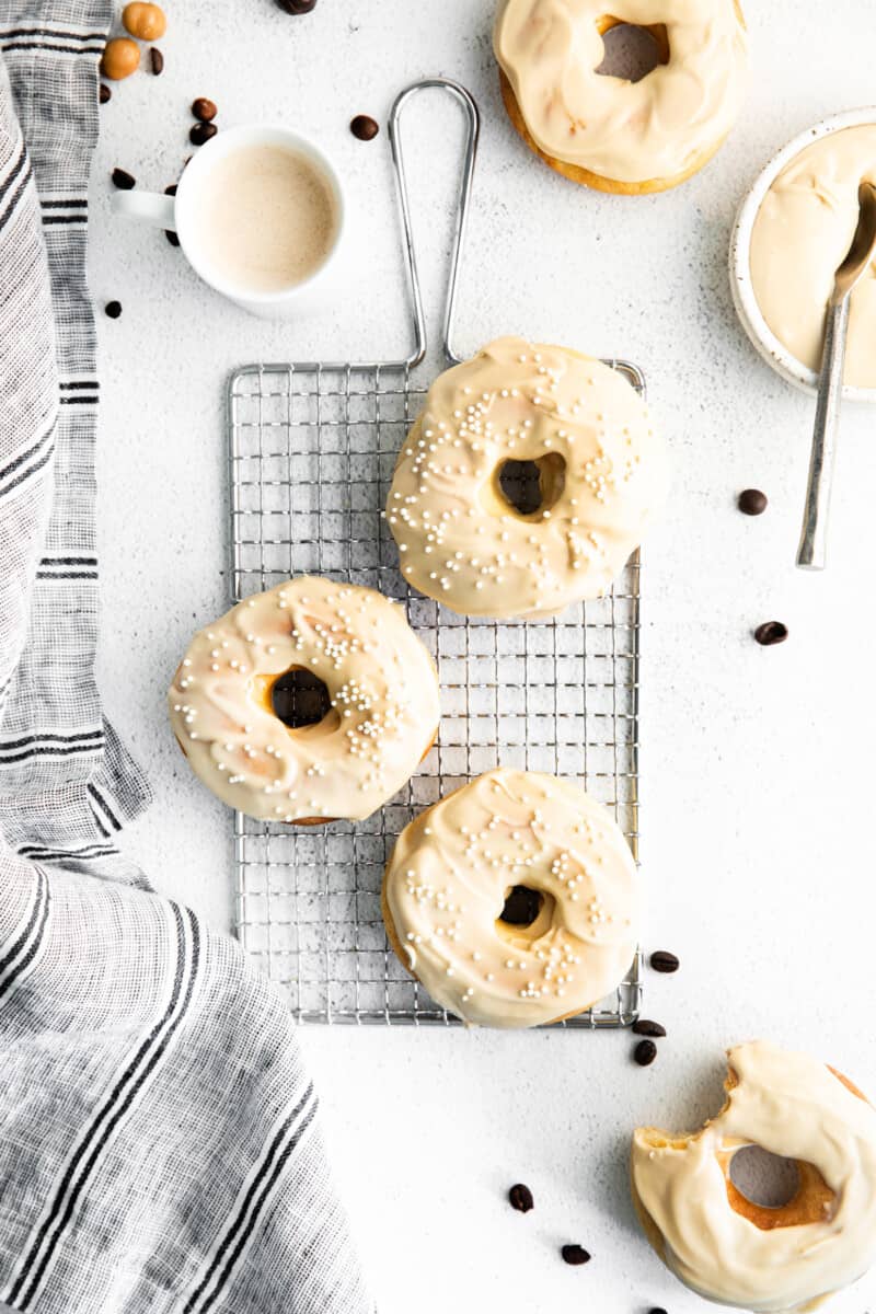 overhead image of coffee donuts with coffee icing and sprinkles on a cooling rack