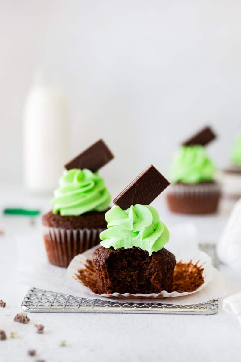 andes mint cupcakes topped with green mint buttercream frosting and andes chocolates with a bite out of one cupcake