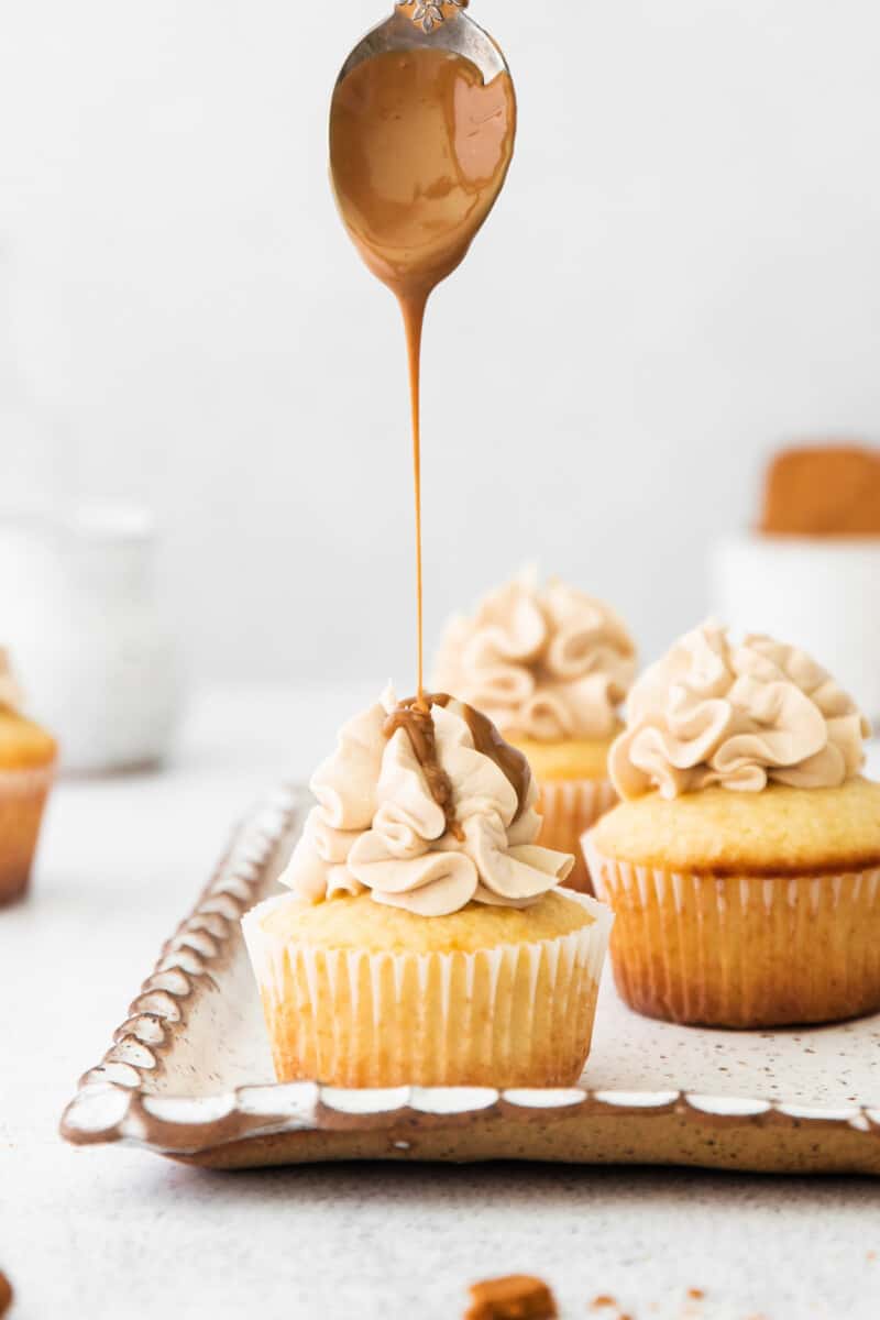 spoon drizzling cookie butter onto cookie butter cupcakes