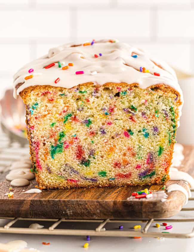 funfetti pound cake with glaze drizzled on top with a slice removed showing the inside texture