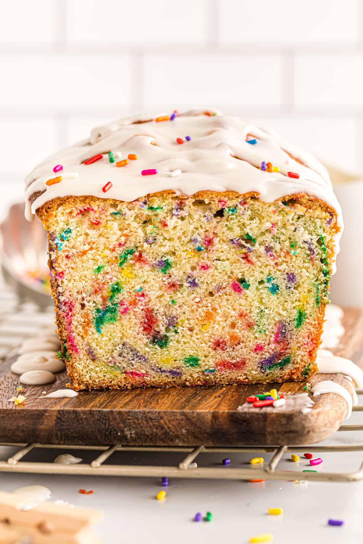funfetti pound cake with glaze drizzled on top with a slice removed showing the inside texture