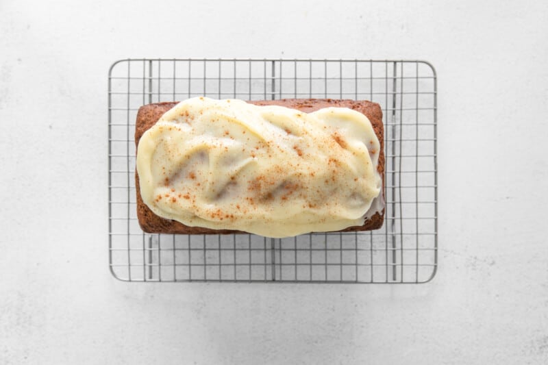 carrot bread topped with cream cheese glaze on a cooling rack