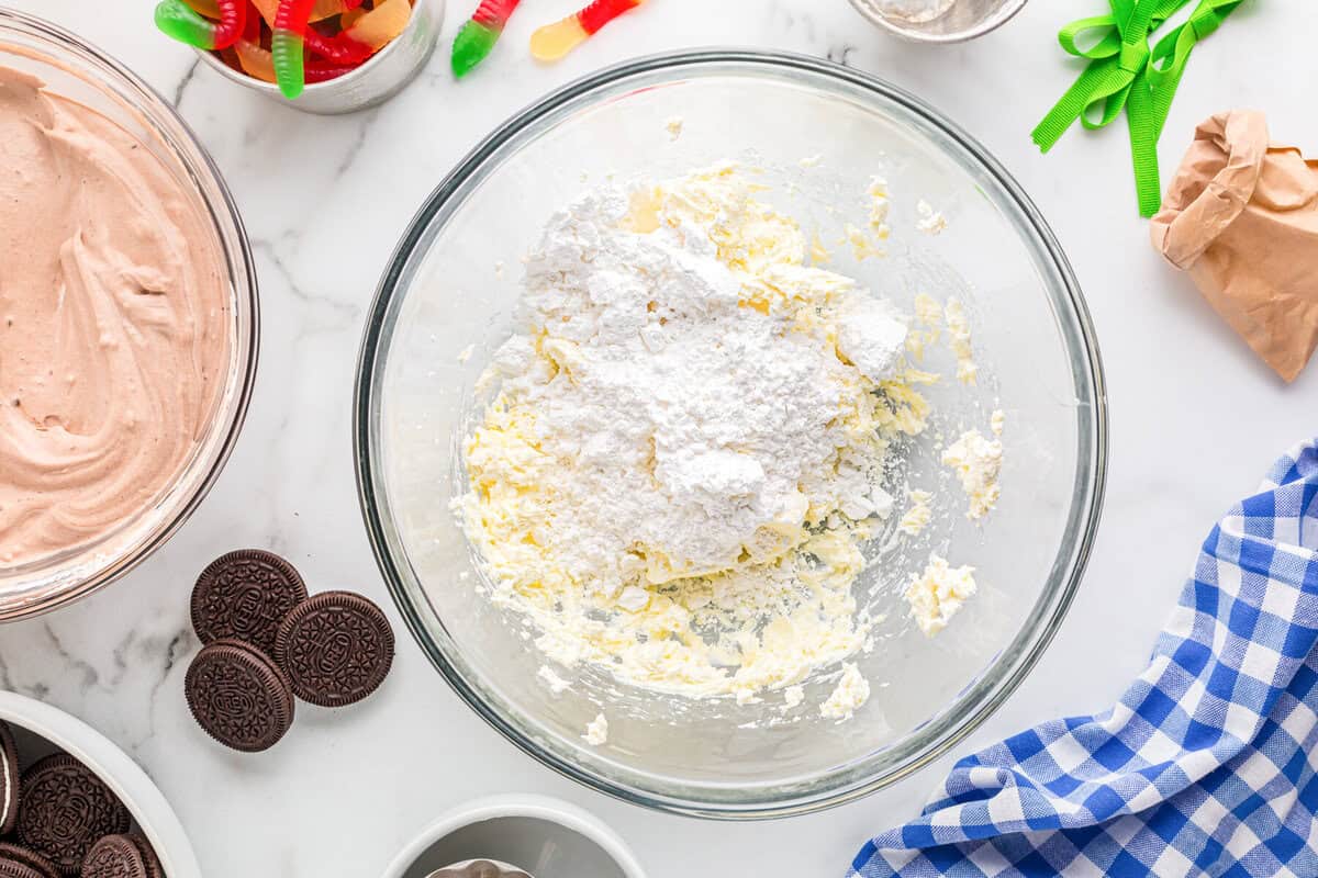 powdered sugar with creamed butter and cream cheese in a glass bowl