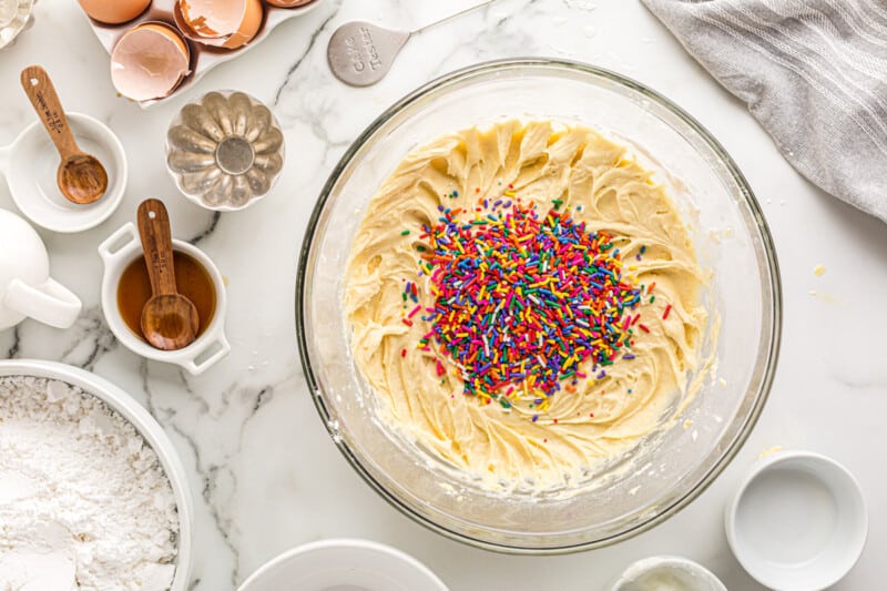 sprinkles added to pound cake batter in a glass bowl