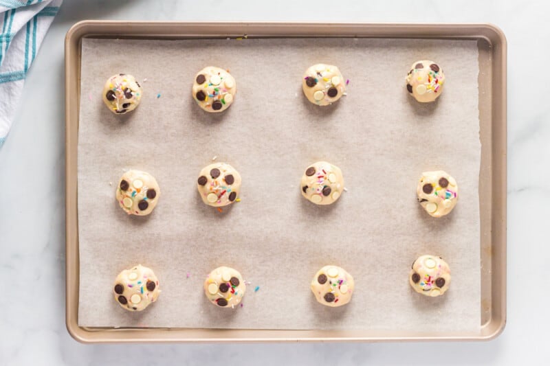 cake batter cookie dough balls on a parchment paper lined baking sheet