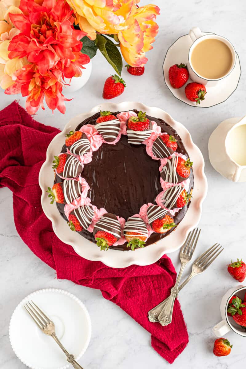 overhead view of chocolate covered strawberry cheesecake on a white cake stand.