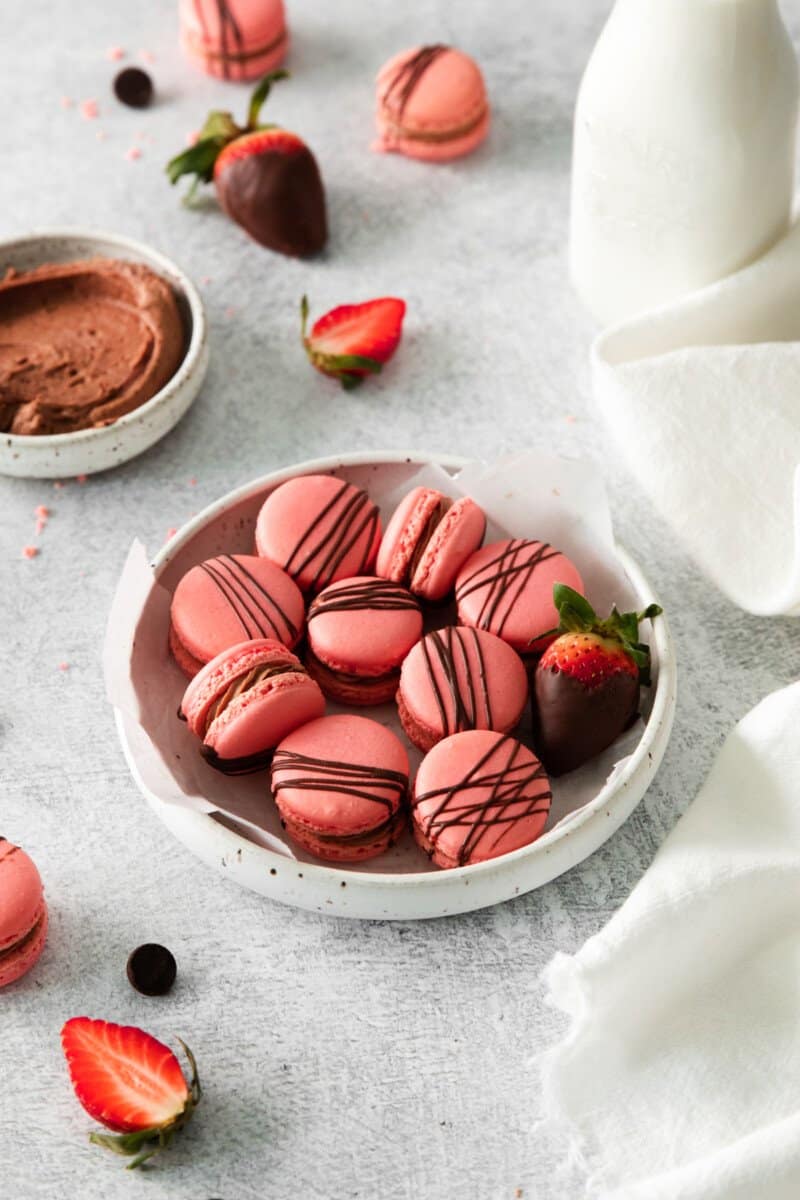 chocolate strawberry macarons in a white bowl.