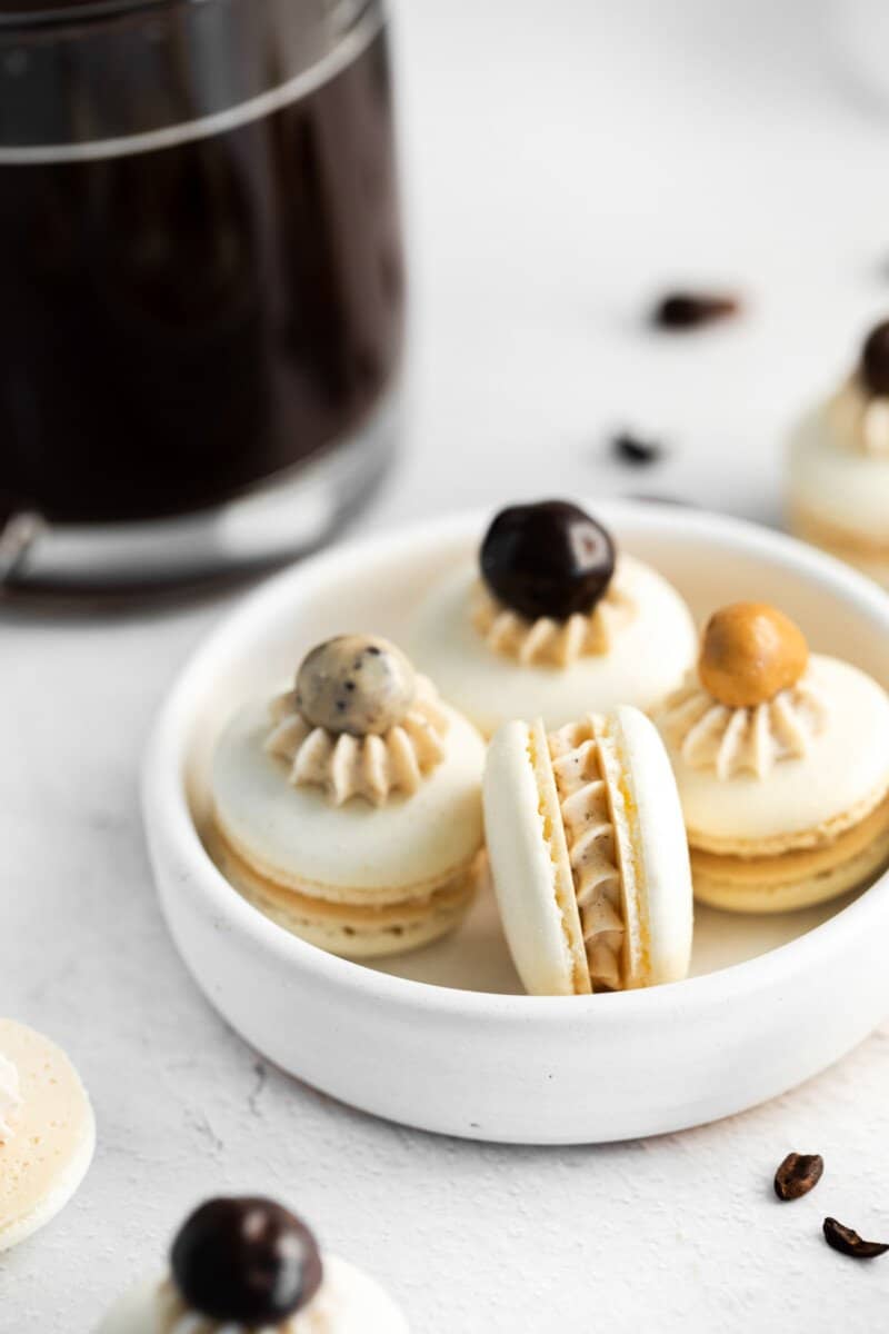 close up view of 4 coffee macarons in a white bowl.