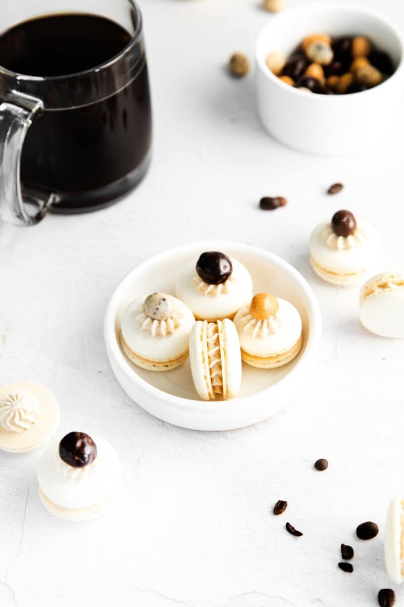 4 coffee macarons in a white bowl.