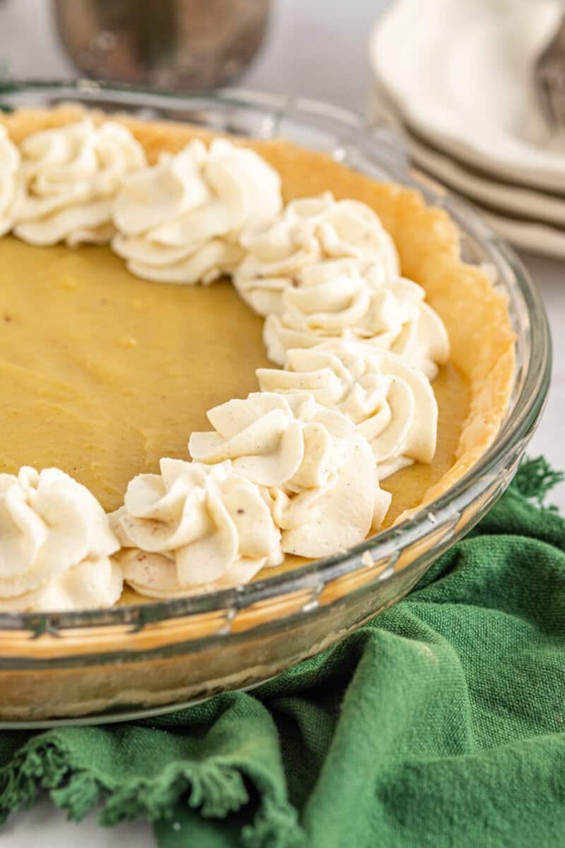 close up of eggnog pie in a glass pie dish on a green table runner.