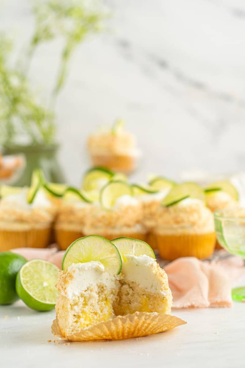 a cut key lime cupcake in front of key lime cupcakes.