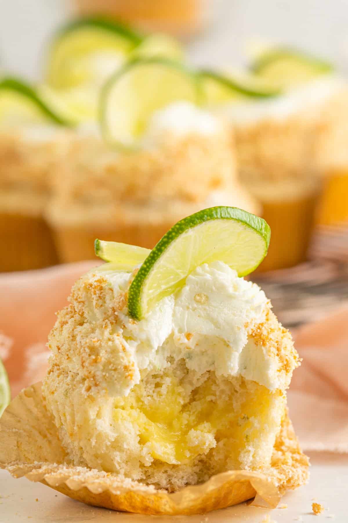 a bitten key lime cupcakes in front of key lime cupcakes.