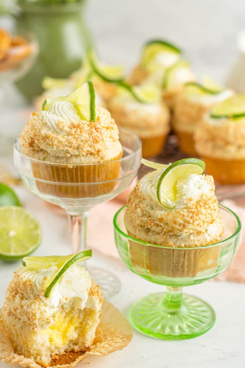 key lime cupcakes in green and clear coupe glasses next to a bitten cupcake.